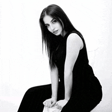 a black and white photo of a woman sitting on a white chair