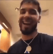 a man with a beard wearing sunglasses and a necklace is smiling and laughing .