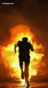 a silhouette of a man running in front of a fire