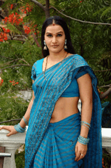 a woman in a blue saree stands on a balcony