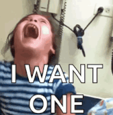 a child is screaming with his mouth open and the words i want one written on his face .