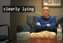 a man sitting on a couch with his arms crossed and a sign that says clearly lying