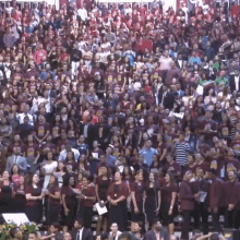 a large crowd of people are gathered in a stadium wearing maroon shirts that say ' jesus loves you ' on them