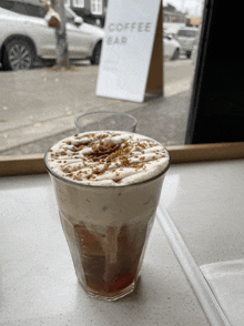 a glass of coffee sits on a counter in front of a sign that says coffee bar