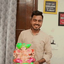 a man holding a statue of ganesha in front of a sign that says " follow your dreams they know the way "