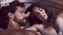 a man and a woman are laying on a bed with taco de ojo written in the corner