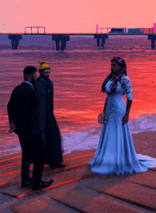 a bride in a wedding dress is standing on a dock with two men