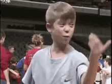 a young boy in a nike shirt is making a funny face while standing in front of a basketball hoop .