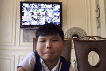 a young boy is sitting in front of a tv with a bunch of pictures on it