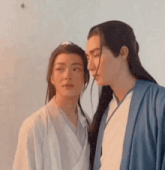 two men with long hair are standing next to each other looking at each other .