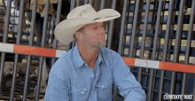 a man wearing a cowboy hat is sitting in front of a fence that says the cowboy way on it