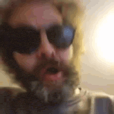 a close up of a man with a beard wearing sunglasses and headphones .