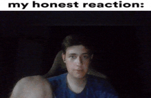 a man in a blue shirt is sitting in a dark room with a caption that says my honest reaction