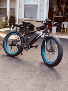 a black bicycle with blue tires is parked in front of a white house