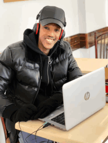 a man wearing headphones sits at a table using an hp laptop