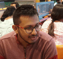 a man wearing glasses and a red shirt is sitting at a table