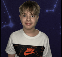 a boy wearing a white nike t-shirt looks at the camera