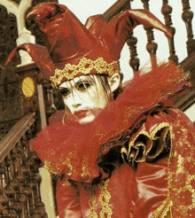 a woman in a red jester costume is standing on a set of stairs