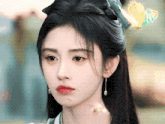 a close up of a woman 's face wearing earrings and a flower in her hair