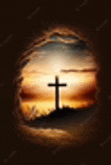 a cross is silhouetted against a sunset sky in a cave .