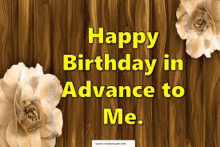 a wooden background with two flowers and the words `` happy birthday in advance to me '' .