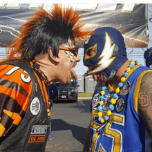 a man wearing a mask with the number 75 on it is standing next to another man