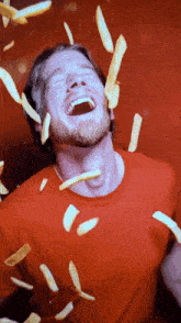 a man is laughing while french fries fall on him