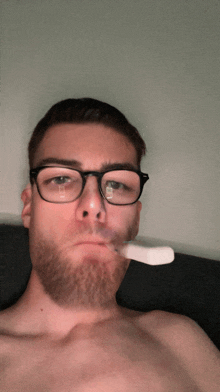 a man with glasses and a beard is holding a toothbrush in his mouth