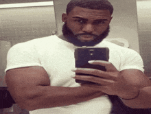 a man with a beard takes a selfie in a bathroom