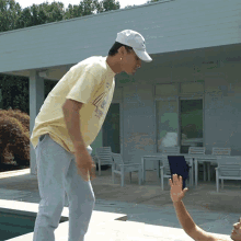 a man wearing a white hat and a yellow shirt with the number 4 on it stands near a pool