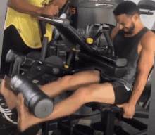 a man is using a leg extension machine with the number 105 on it