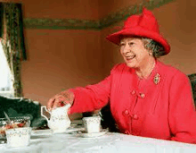 a woman in a red hat is pouring tea into a cup at a table .