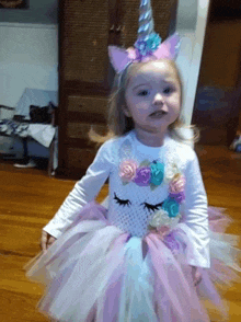 a little girl dressed in a unicorn costume with flowers on her head