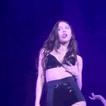 a woman in a black bra and fishnet stockings singing into a microphone