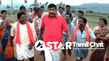 a man in a red shirt stands in a crowd of people with a star tamil chat logo in the corner
