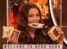 a woman is holding cheese in her mouth and the words welcome to nerd herd are below her