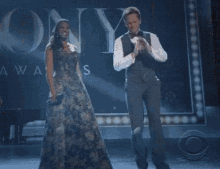 a woman in a long dress is standing on a stage in front of a sign that says ' tony awards '