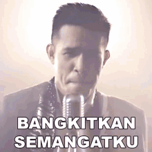 a man singing into a microphone with the words " bangkitkan semangatku " above him