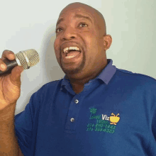 a man singing into a microphone wearing a blue shirt with the word viz on the front