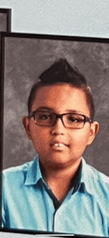 a boy wearing glasses and a blue shirt is in a picture frame