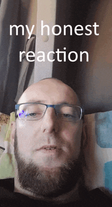 a bald man with glasses and a beard is laying on a bed with the words " my honest reaction " above his head