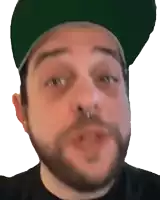 a man with a beard and a green hat looks at the camera