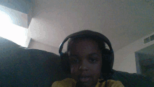 a young boy wearing headphones and a microphone sits on a couch