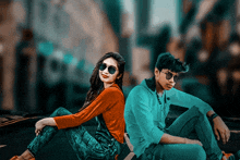 a boy and a girl are sitting back to back on a sidewalk