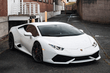 a white lamborghini is parked in a narrow alleyway