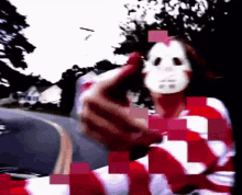 a person wearing a mask and a red and white striped shirt is standing on a street .