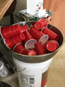 a bowl of red cups sits on top of a white bucket of soy sauce