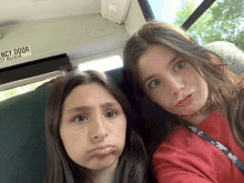 two girls are making faces in front of an emergency door on a bus