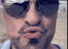 a man with a beard is wearing sunglasses and making a face .