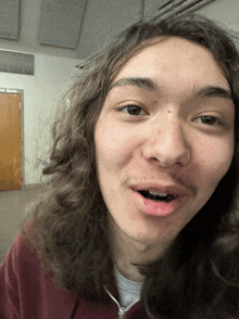 a young man with long hair and a mustache is making a funny face